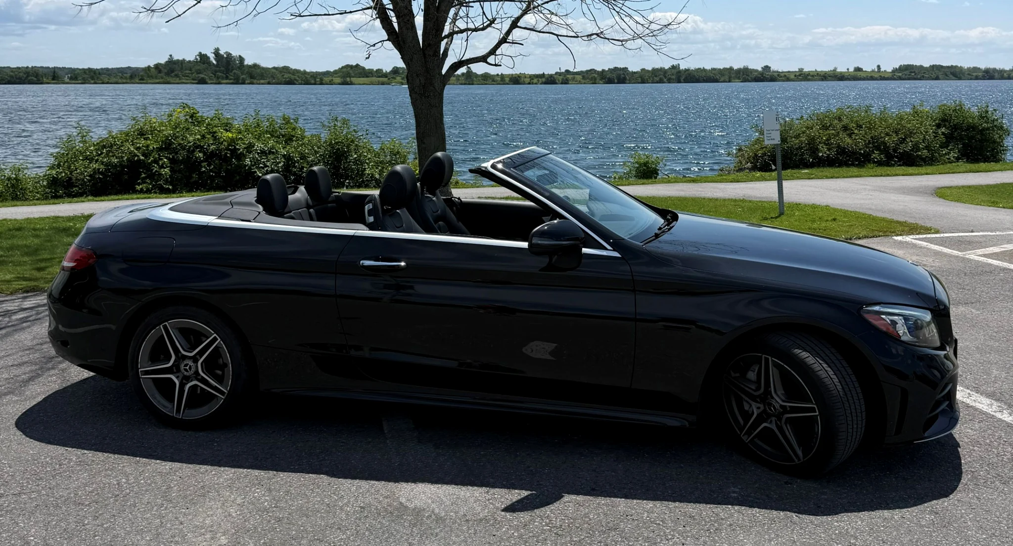 Side profile of the black Mercedes Cabriolet beside the water
